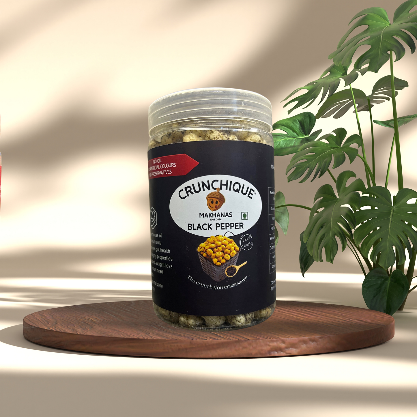Crunchique Black Pepper Makhana in clear jar with black label on wooden tray with green plant