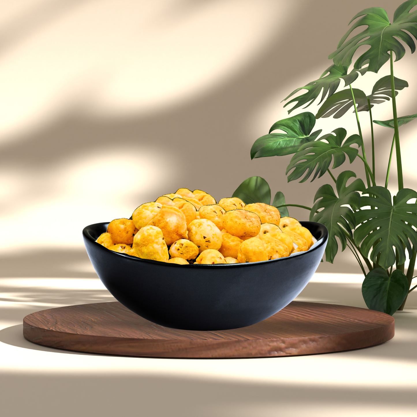 Black bowl filled with crunchy cheddar cheese makhana on a wooden tray with green leaves in the background