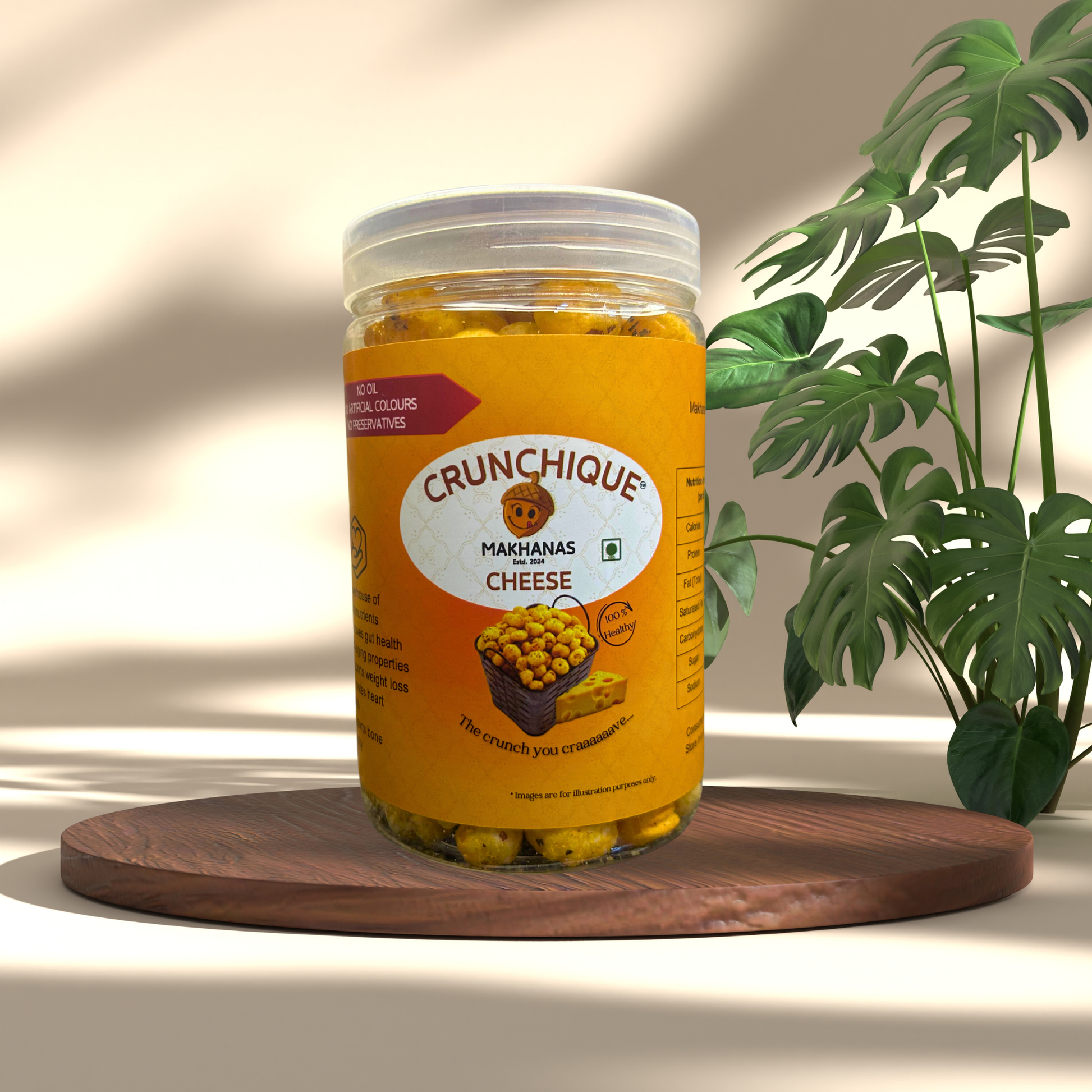 Crunchique cheddar cheese makhana in a clear jar with yellow label on wooden tray beside green plant