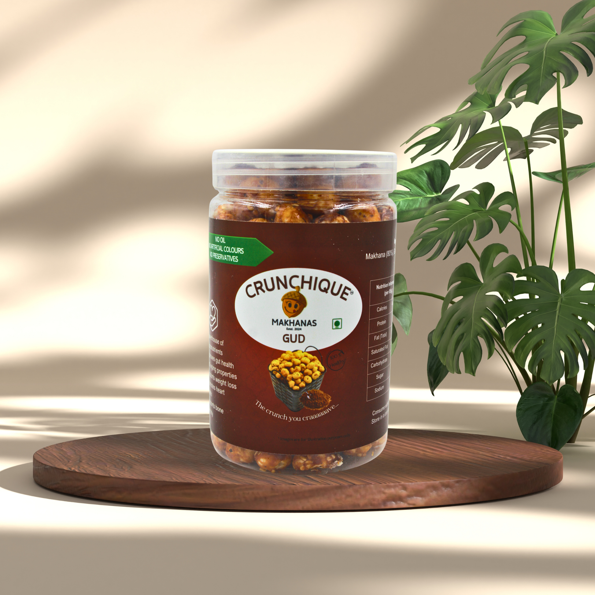 Crunchique Gud Makhana in a clear jar on wooden board with green plant backdrop Gud Makhana Sweet Healthy Guilt-Free